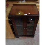 A reproduction mahogany music cabinet with lift-top and pair of glazed panel doors under