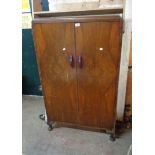 An 83cm 1930's walnut veneered low wardrobe with shelf and drawer fitted interior enclosed by a pair