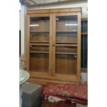 A 1.2m Victorian pine two part book cabinet with glazed top over a base with pair on panelled
