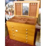 A wooden jewellery box of chest of drawers form with lift up mirror inset top