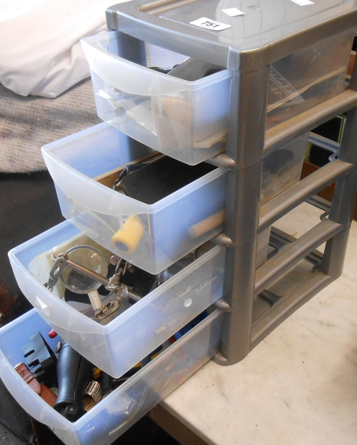 A plastic crate of drawers containing jewellery and watch repair equipment