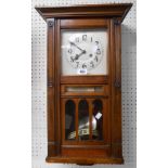 An early 20th Century walnut cased wall clock with visible pendulum and date aperture and eight