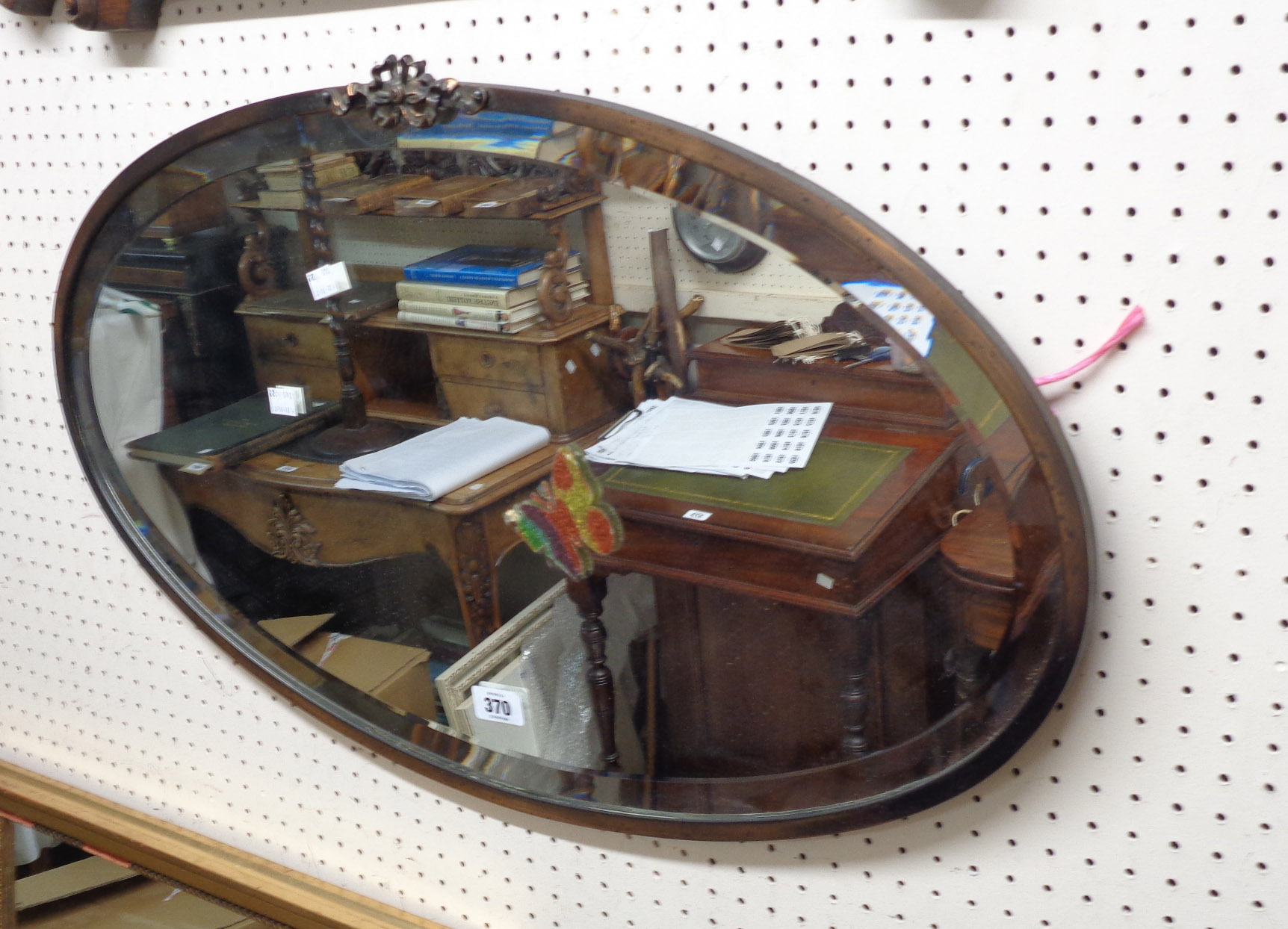 A vintage coppered metal framed bevelled oval wall mirror with applied decoration