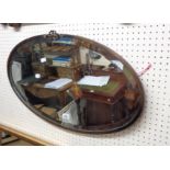 A vintage coppered metal framed bevelled oval wall mirror with applied decoration