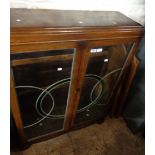 A 92cm polished oak display cabinet with glass shelves enclosed by a pair of Art Deco leaded