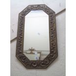 A vintage embossed brass clad framed octagonal wall mirror with decorative border