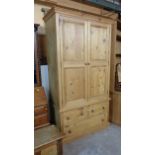 A 1.18m modern waxed pine two part double wardrobe with shelf and hanging space enclosed by a pair