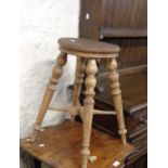 An antique stained wood stool with warped circular top, set on turned supports