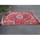 A machine made rug with central floral pattern and similar border on red ground - 2.8m x 2m