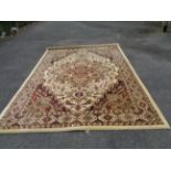 A large machine made Turkish rug with maroon, olive and black motifs on ivory ground - 3.3m X 2.4m