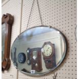 A vintage frameless bevelled oval wall mirror with chrome plated plate clips