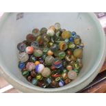 A plastic tub containing a quantity of vintage marbles