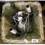 A wicket waste paper basket containing a modern Toleware style wall lamp and a ceramic table lamp