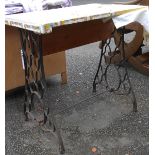 An antique sewing machine table with cast iron stand and wooden top