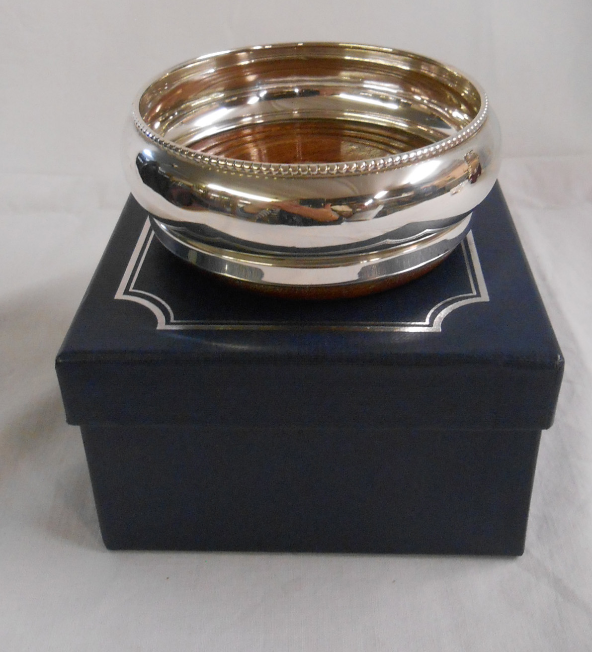 A modern silver wine coaster by Broadway & Co., with wooden base - Birmingham 2000