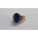 A 375 gold ring, set with large central lapis lazuli cabochon and flanking rows of tiny diamonds