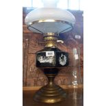 A vintage printed ceramic and brass table oil lamp with spare chimney and milk glass shade