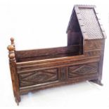 A 97cm antique carved oak hooded cradle with scaled slate effect to gabled top, turned finials to