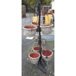 A wrought iron plant holder with six hanging pots