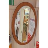 A retro teak backed wall mirror with applied oval plate