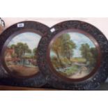 A pair of early 20th Century pressed tin decorative wall plaques with central litho printed scene