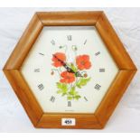A modern wooden framed hexagonal wall timepiece with hand painted poppy decoration to dial and