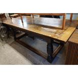 A 2.13m old stained oak refectory dining table with thick bracketed plank top and carved frieze, set
