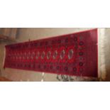 A Belgian machine made wool runner with repeat gul motifs on red ground - edge wear - 2.7m X 68cm