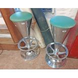 A pair of vintage polished aluminium bar stools with tapered stems, circular foots rails and heavy