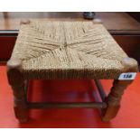 A oak framed foot stool with remains of woven seagrass top