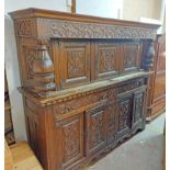 A 2.1m 20th Century carved oak court cupboard with decorative frieze and triple cupboard doors