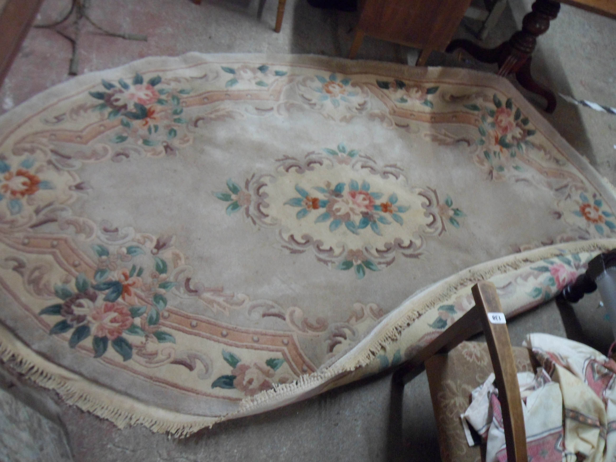 A vintage Chinese washed wool oval rug with floral motifs and decorative border on beige ground -