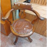 An early 20th Century stained oak swivel office chair with pierced splat back and remains of studded