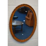 AN EARLY TO MID 20TH CENTURY OAK OVAL BEVELLED EDGE WALL MIRROR, 97cm x 72cm