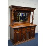 AN EARLY 20TH CENTURY WALNUT MIRROR BACK SIDEBOARD, foliate decoration, overhanging top supported by