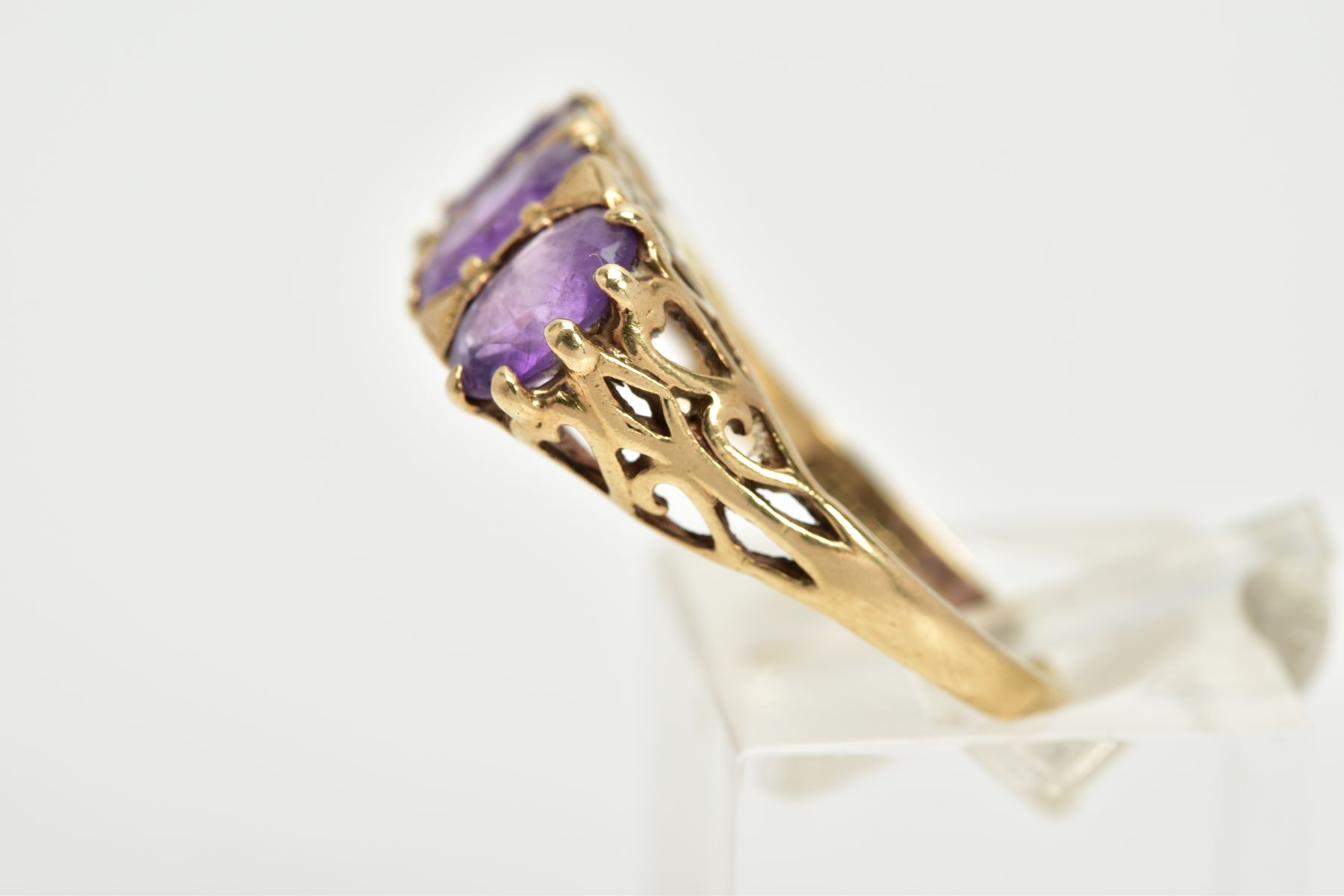 A 9CT GOLD THREE STONE AMETHYST RING, three claw set oval cut amethysts, within a raised openwork - Image 2 of 3