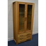 A MODERN GOLDEN OAK GLAZED TWO DOOR DISPLAY CABINET, two glass shelves above three drawers, width
