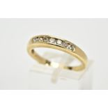 A YELLOW METAL DIAMOND HALF ETERNITY RING, designed with a row of channel set round brilliant cut