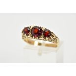 A 9CT GOLD THREE STONE GARNET RING, set with three graduated circular cut garnets, within a scroll