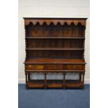 A REPRODUCTION OAK DRESSER the top with a wavy apron above the plate rack shelves the base with