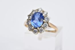 A 9CT GOLD CLUSTER RING, designed with a central oval cut blue sapphire, within a circular cut cubic