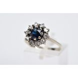 A WHITE METAL SAPPHIRE AND DIAMOND CLUSTER RING, designed with a central circular cut blue