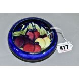 A MOORCROFT POTTERY LIPPED BOWL, the interior decorated with Wisteria (plums) on a blue ground,