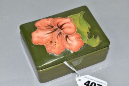 A MOORCROFT POTTERY RECTANGULAR TRINKET BOX AND COVER, the lid with a coral hibiscus, on a green