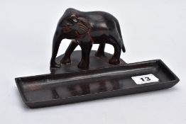 A BRONZE DESK TOP ORNAMENTAL PEN HOLDER, in the form of an elephant in its stride, a top a