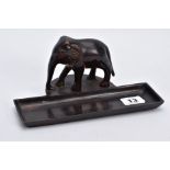 A BRONZE DESK TOP ORNAMENTAL PEN HOLDER, in the form of an elephant in its stride, a top a