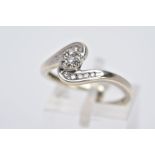 A 9CT WHITE GOLD CROSS OVER DIAMOND RING, designed with a central circular section set with seven