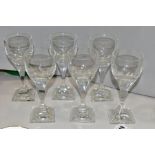 A SET OF SIX DAUM CLEAR GLASS WINE GLASSES, the facetted bowls on a square hour glass shaped stem