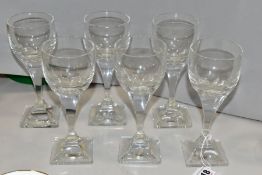 A SET OF SIX DAUM CLEAR GLASS WINE GLASSES, the facetted bowls on a square hour glass shaped stem