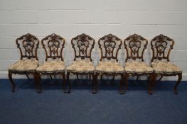 A SET OF SIX VICTORIAN WALNUT CHAIRS, with elaborate foliate carved backs, on cabriole front legs,